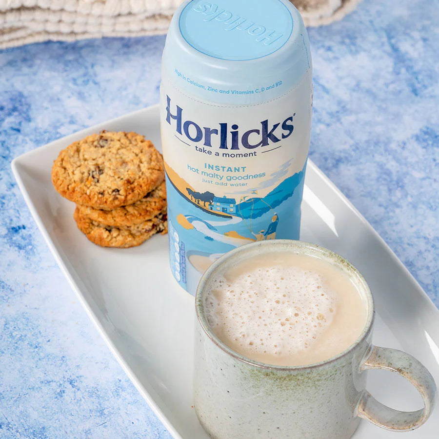 Horlicks instant drink container with a cup of coffee and cookies on a tray