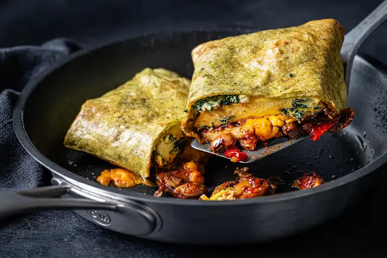 Two burritos being served with a Can of mixed M&S beans on a black pan with a dark background 