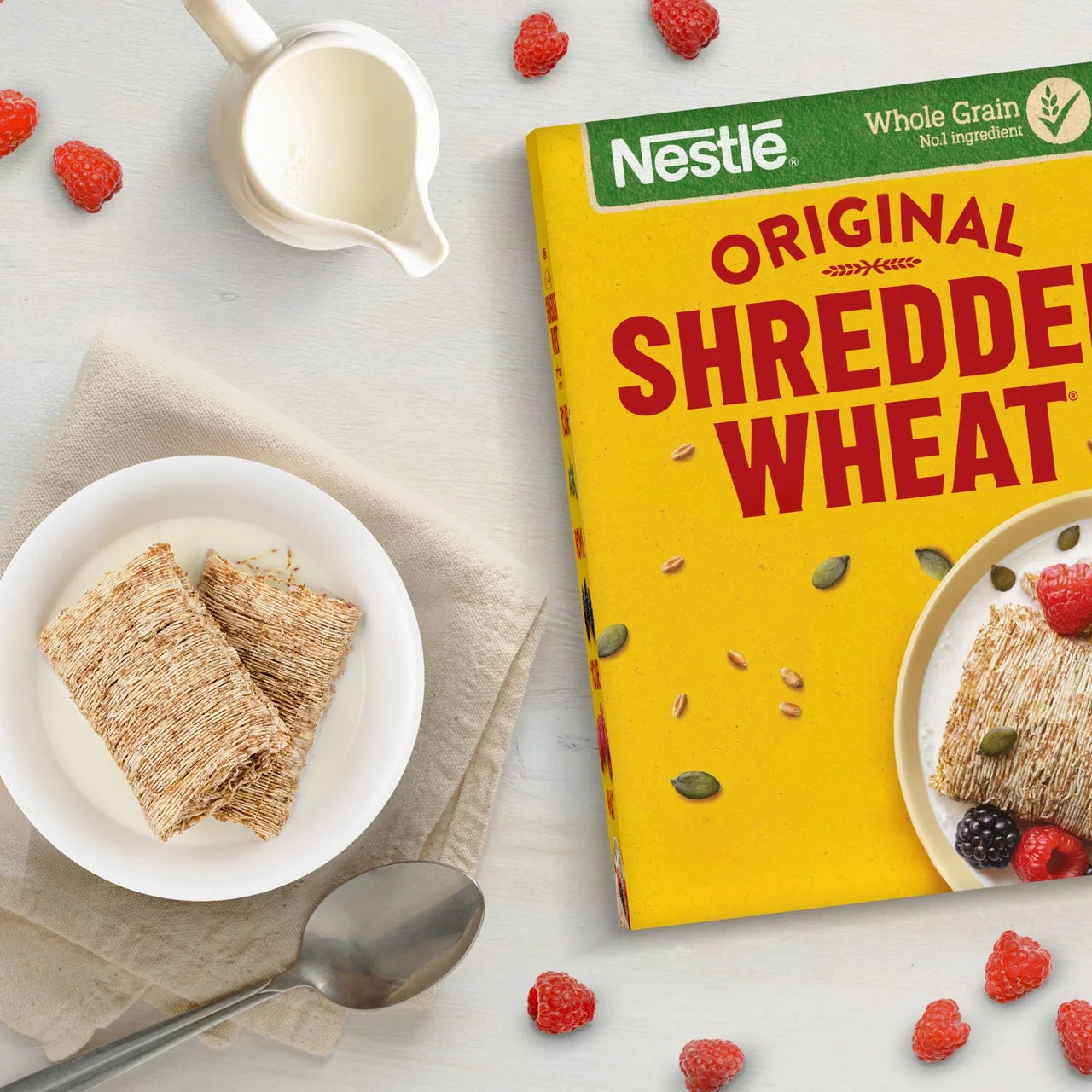 Nestle Shredded Wheat cereal box with a bowl of cereal and raspberries on a light background