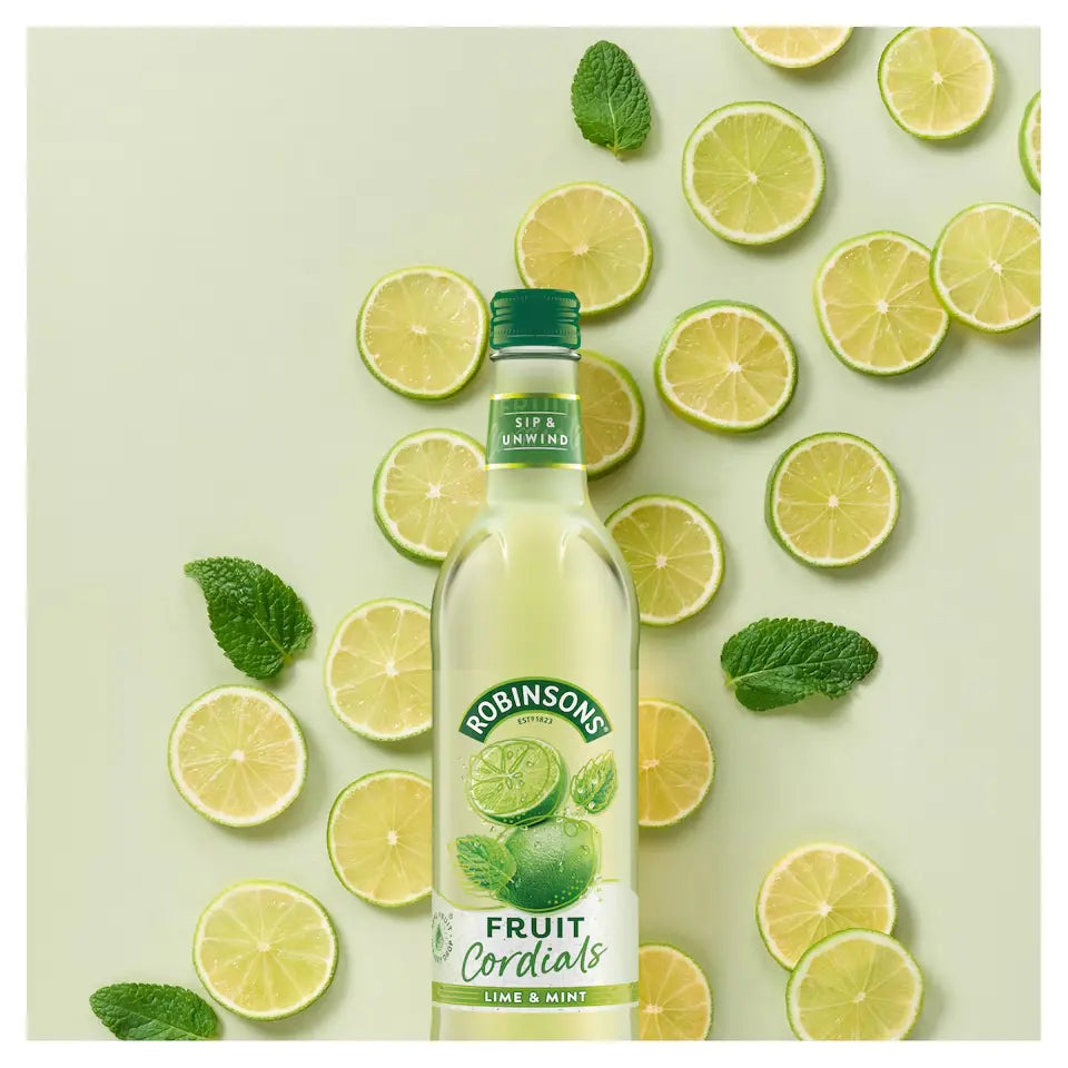 Bottle of Robinsons Fruit Cordials Lime & Mint with lime slices and mint leaves on a light green background