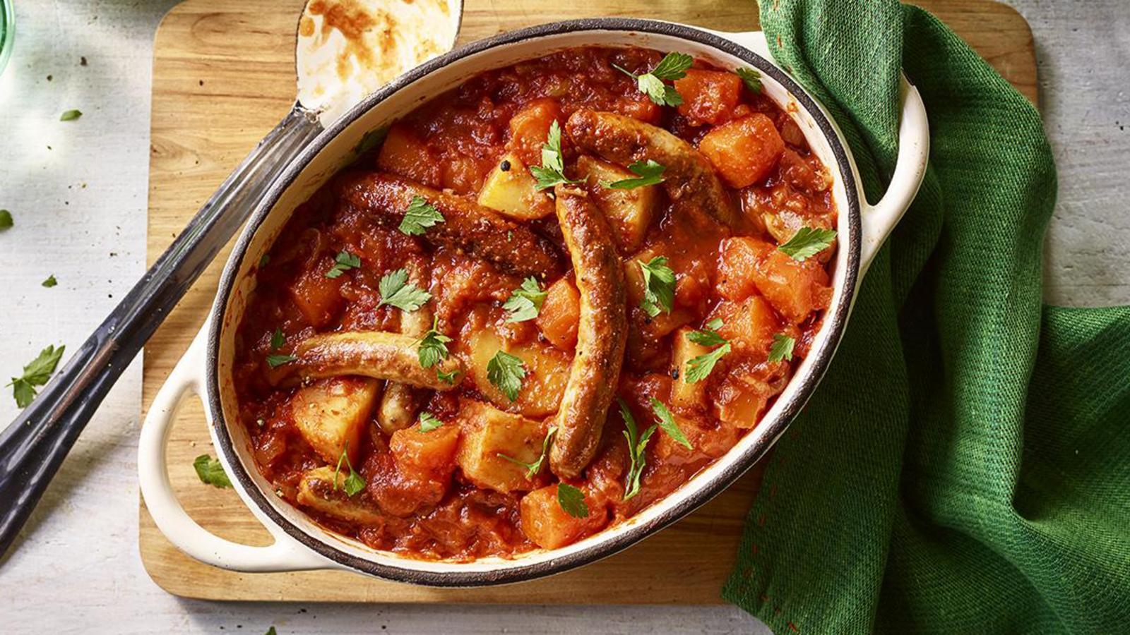 Stew with vegetables in a bowl on a wooden cutting board