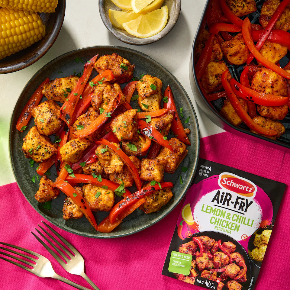 Plated dish of air-fried lemon and chilli chicken with peppers and a package of Schwartz Air-Fry Lemon & Chilli Chicken on a pink napkin.