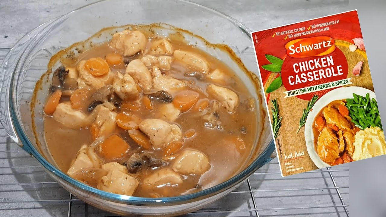 Chicken casserole in a glass dish with a package of Schwartz Chicken Casserole mix on a wooden surface.