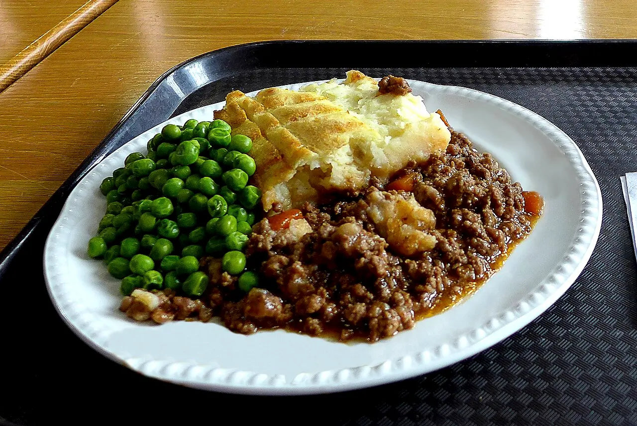Shepherd's pie with peas on a white plate