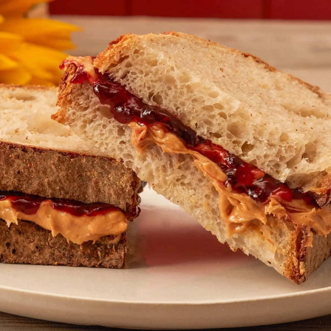 Peanut butter and jelly sandwich on a white plate with a blurred background