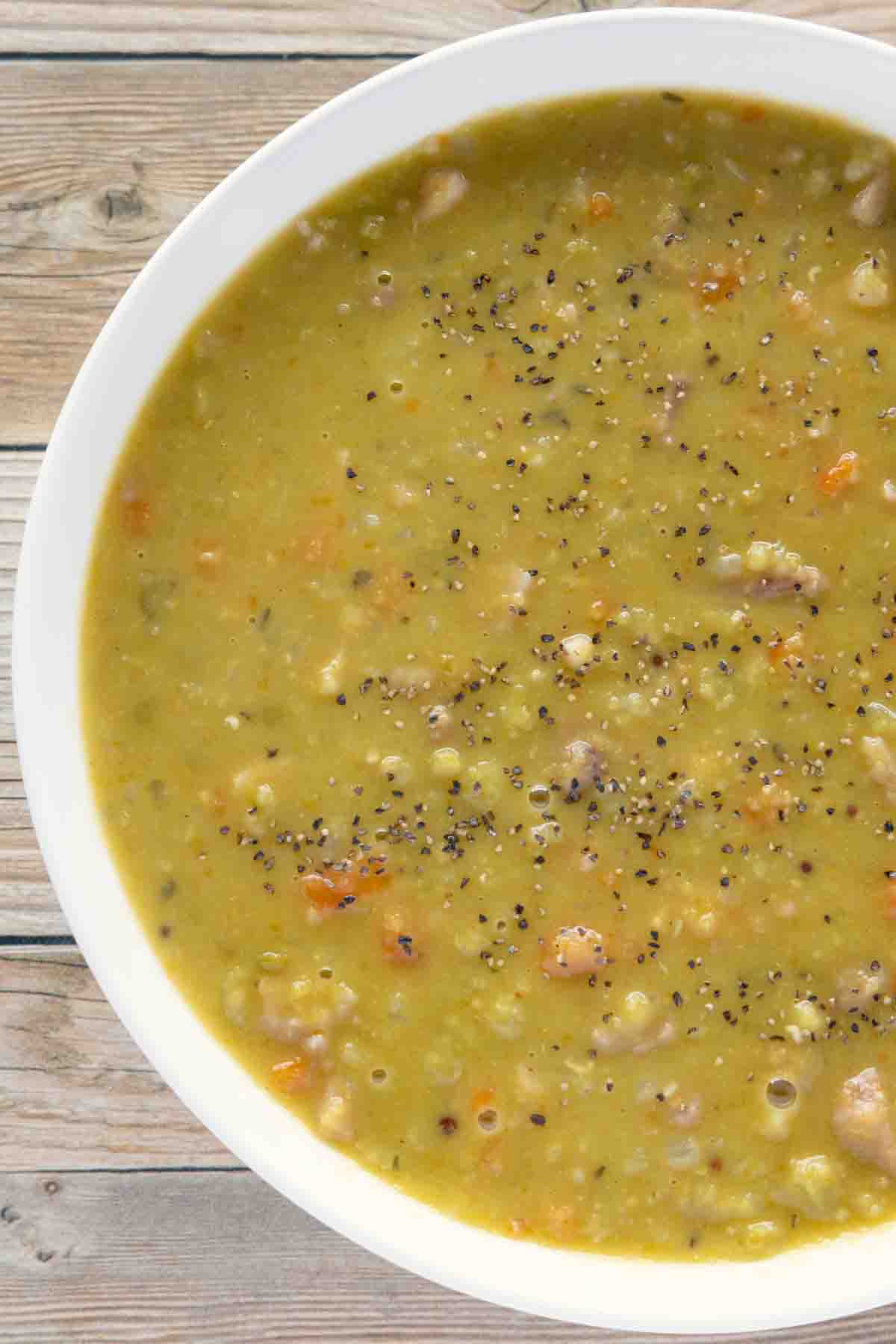 White bowl of split pea soup on a wooden table