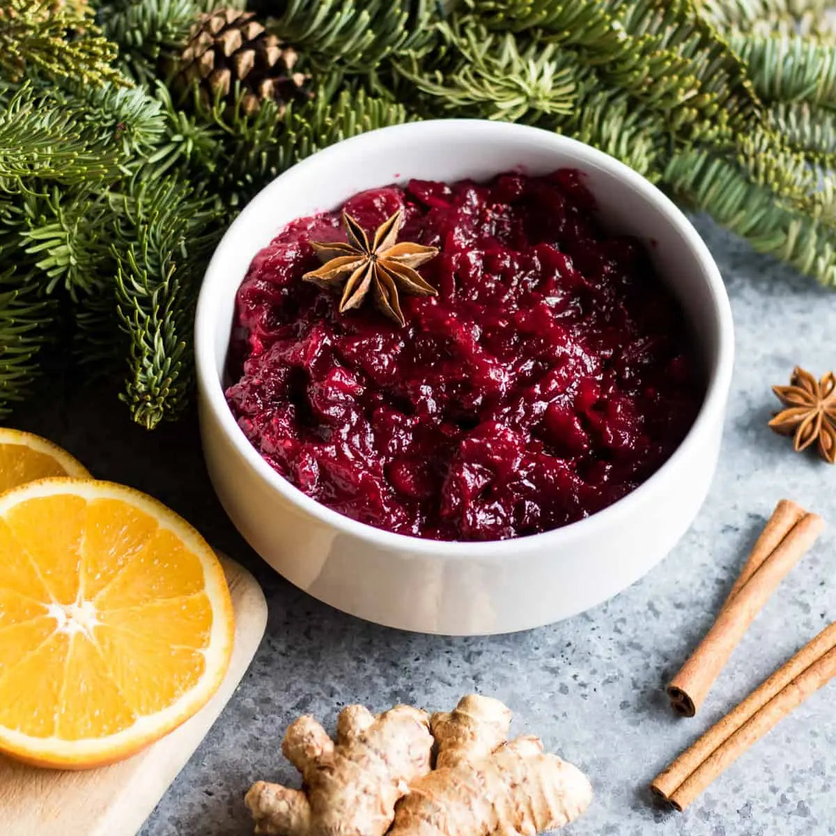 Bowl of cranberry sauce with garnishes on a festive background