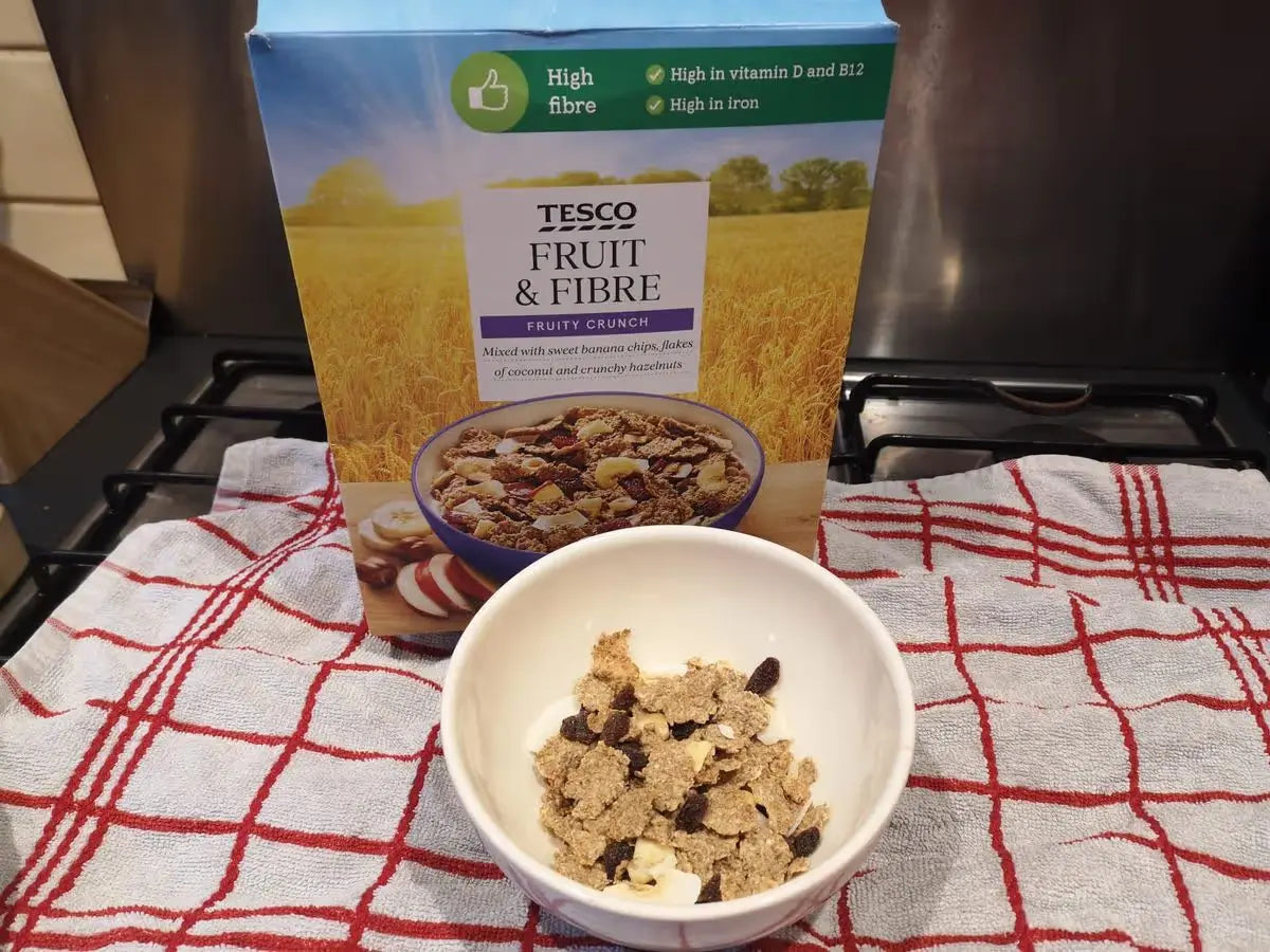 Tesco Fruit & Fibre cereal box with a bowl of cereal on a checkered towel.