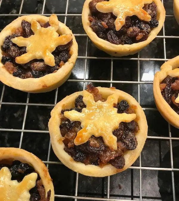 Mini pies with fruit filling and pastry stars on a cooling rack