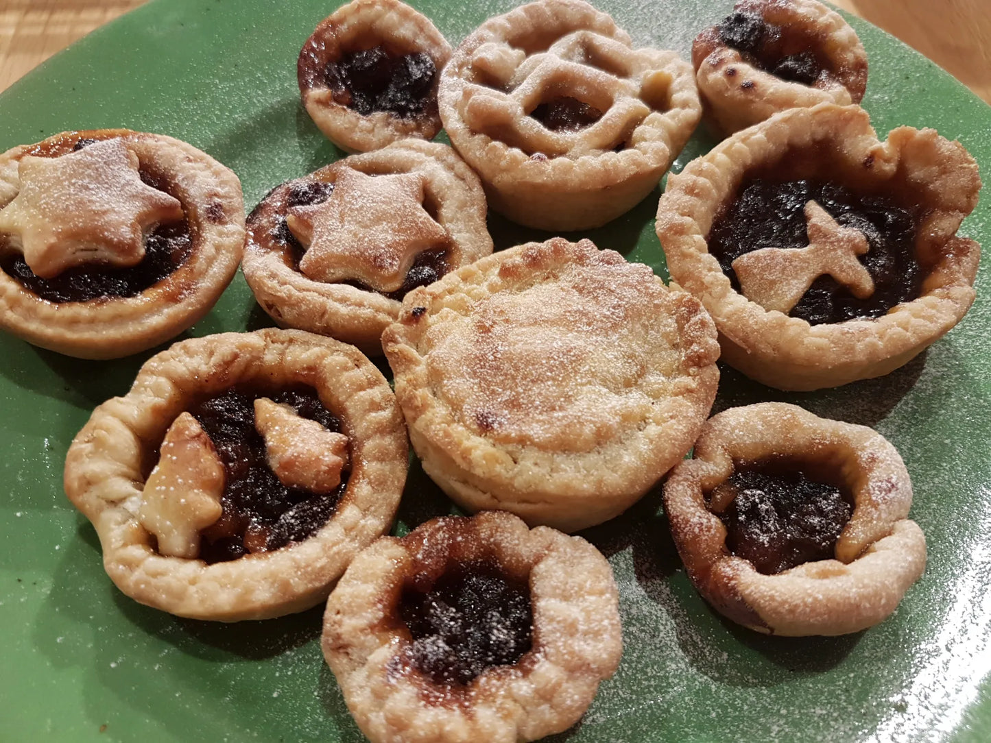 Mince pies with star and cross-shaped crusts on a green plate
