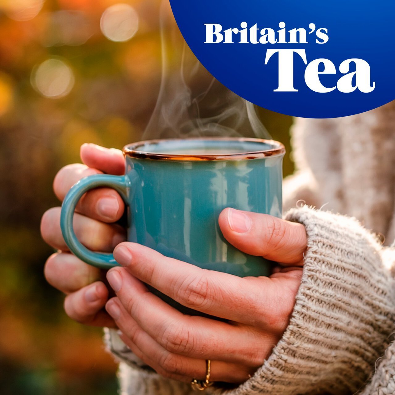Person holding a steaming blue mug with 'Britain's Tea' logo in the corner